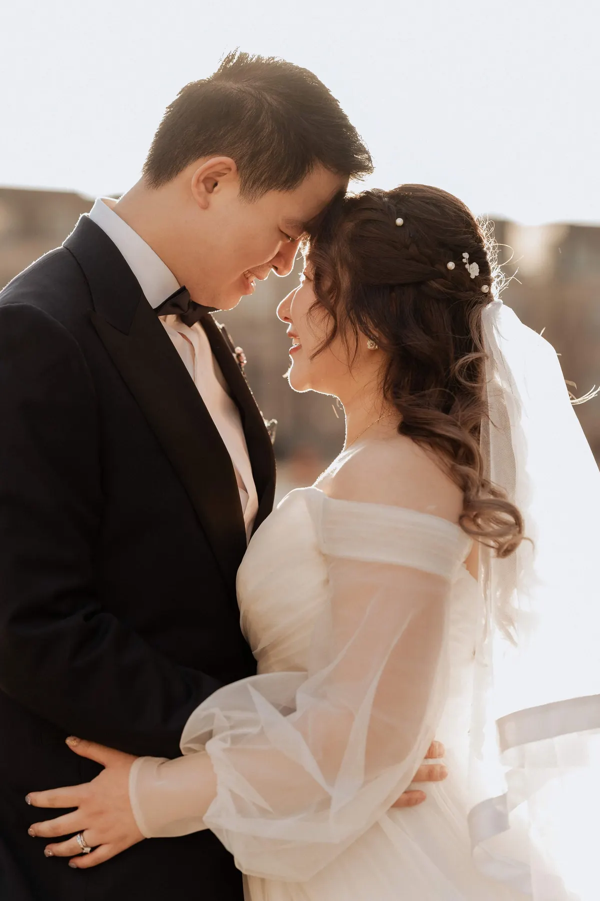 Bride and groom in a quiet moment, foreheads touching, golden hour